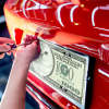 Installing custom money front license plate on red car, personalized car decor, $100 bill design