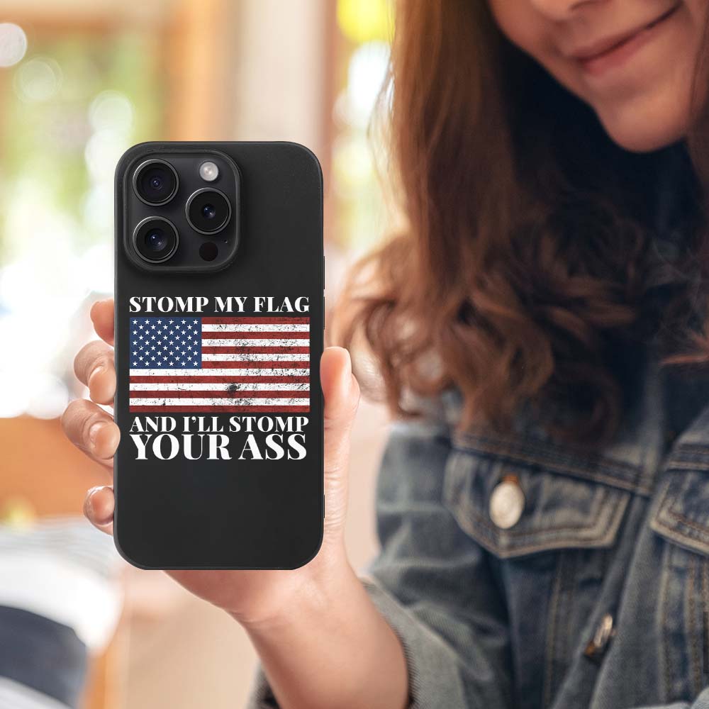 iPhone 15 Pro case with American flag, black TPU, text "STOMP MY FLAG AND I'LL STOMP YOUR ASS", shockproof