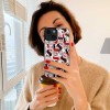 iPhone 15 case with a white and red pattern, held by a woman in a mirror selfie.
