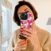 Woman holding iPhone 15 with floral print case, card slot design, stylish and full protection.