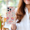 Floral iPhone 14 case held by a woman, PC plastic, scratch-resistant, precise cutouts.