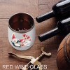 White stainless steel insulated cup with cat and penguin design, filled with red wine, Inkedjoy.