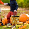 Child holding Halloween tote bag with ghost and pumpkin pattern, perfect for trick-or-treating.