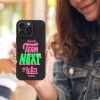 Black iPhone 15 case featuring 'TEAM NEXT @ Lolla' design, TPU material, shockproof protection.