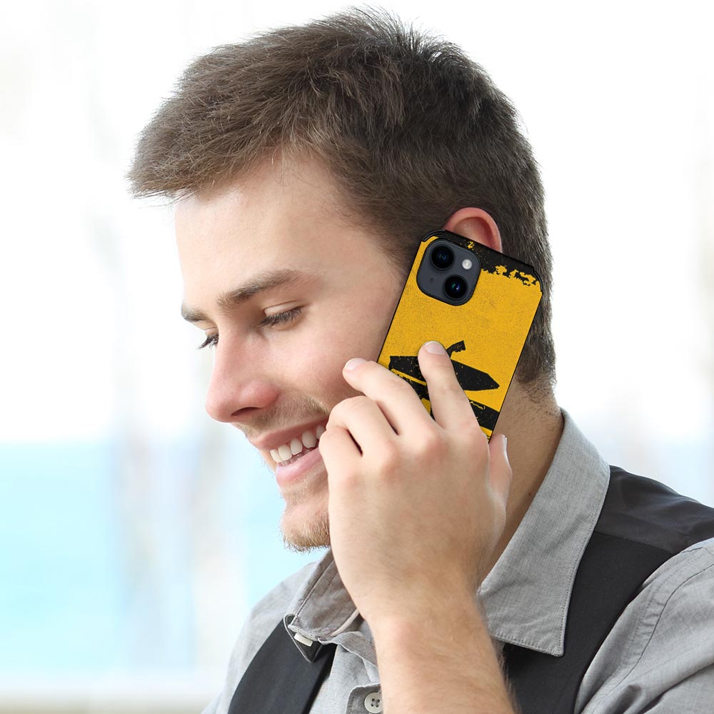Man talking on iPhone 14 with yellow fiber skin case, 'ALWAYS HUNGRY' graphic, stylish.