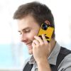 Man talking on iPhone 14 with yellow fiber skin case, 'ALWAYS HUNGRY' graphic, stylish.
