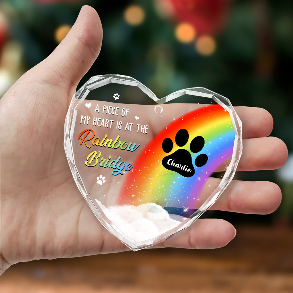 Clear glass heart ornament with rainbow and paw print design, held in hand, a memorial gift for dog moms.