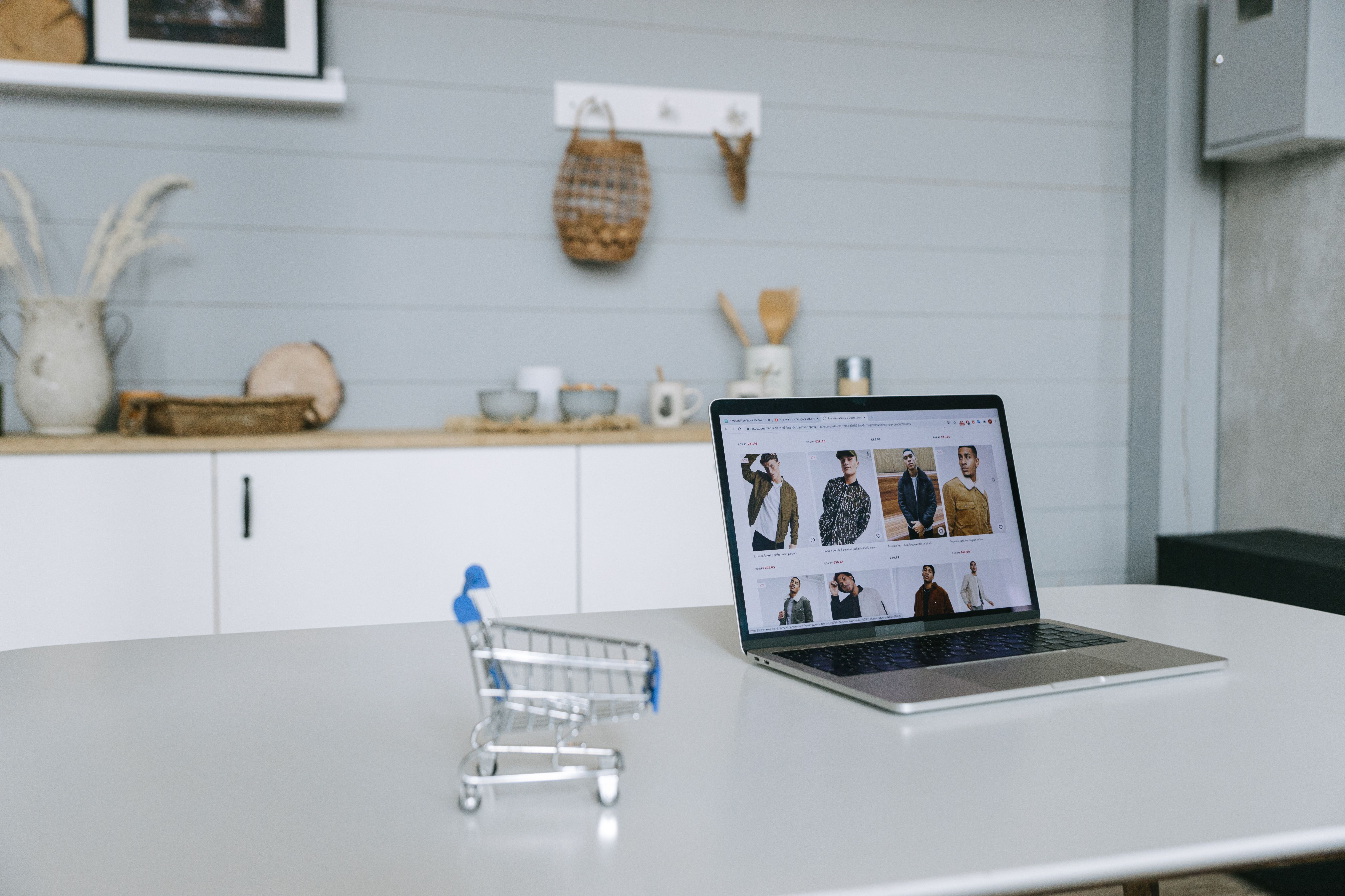 Evaluating which is better Shopify or BigCommerce on a laptop beside a mini shopping cart.