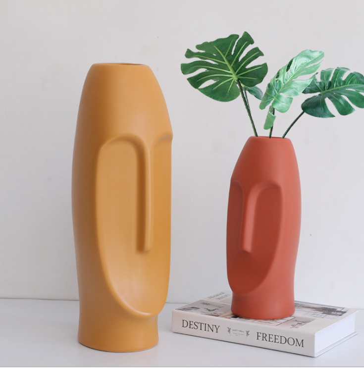 Mustard and terracotta face vases with sculpted relief in close-up
