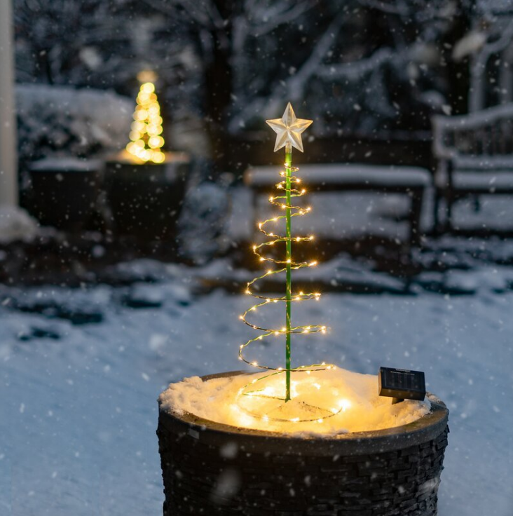 Glowing solar LED Christmas tree lighting a snowy garden at night