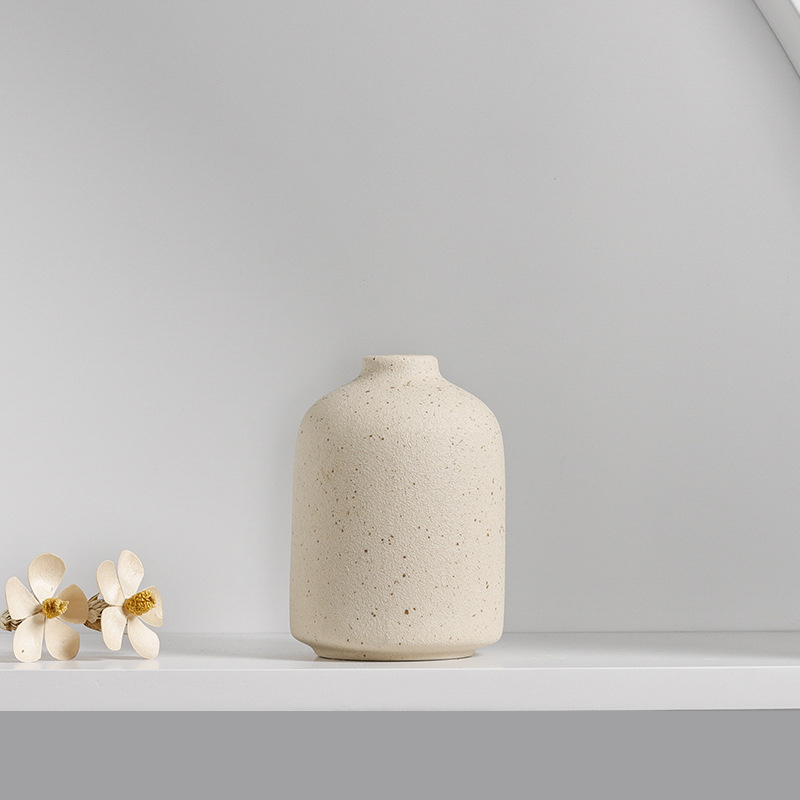 Styled shelf with ceramic vases and dried stems in soft light