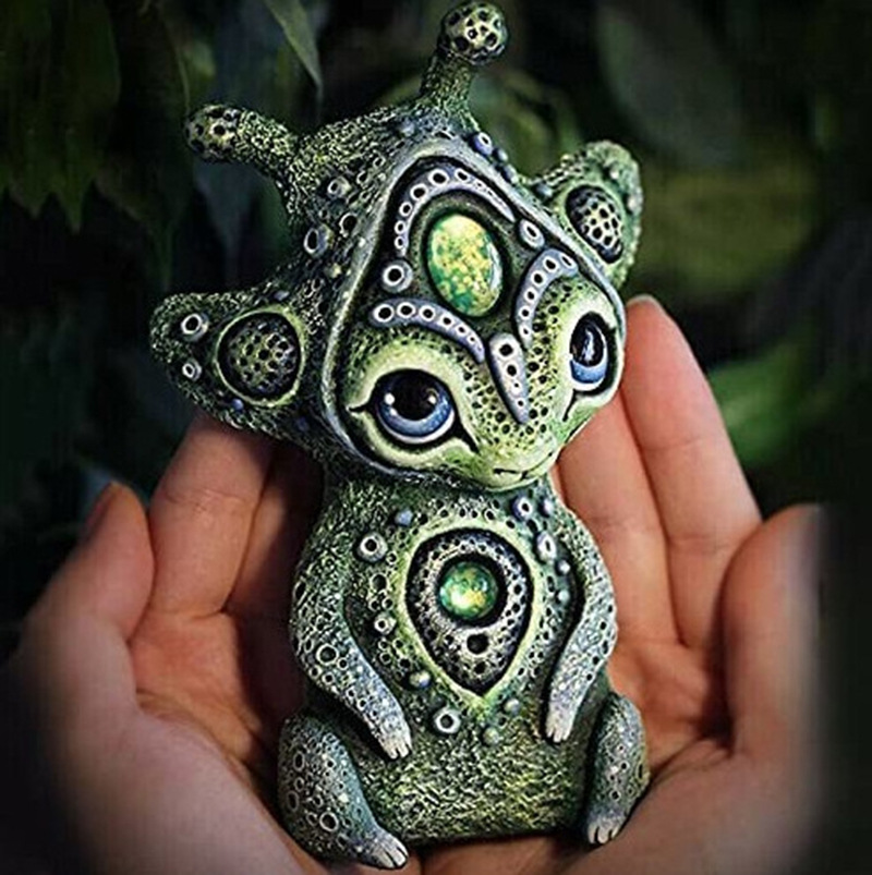 Small green resin creature held in an open palm to show its compact size