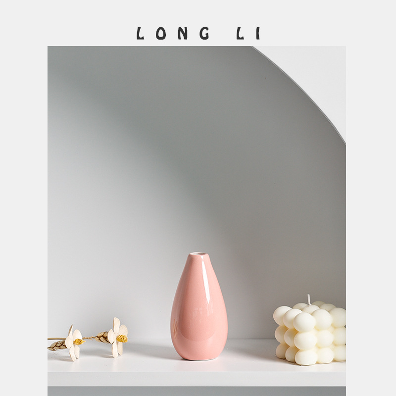 Pastel teardrop vase styled beside decor objects on a shelf