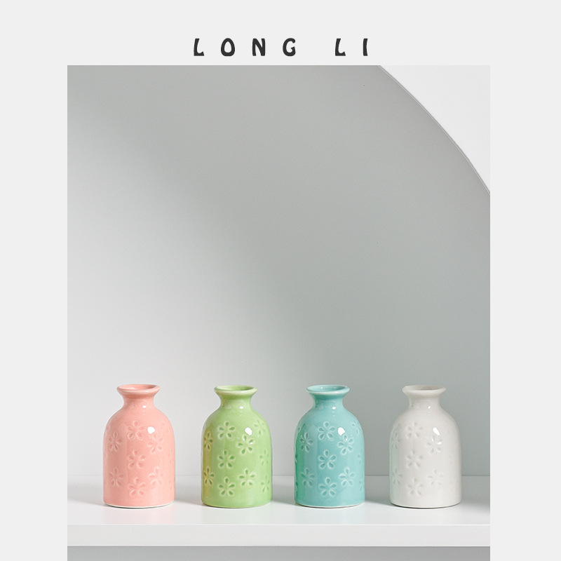 Pastel mini ceramic vases lined up with embossed daisy pattern visible