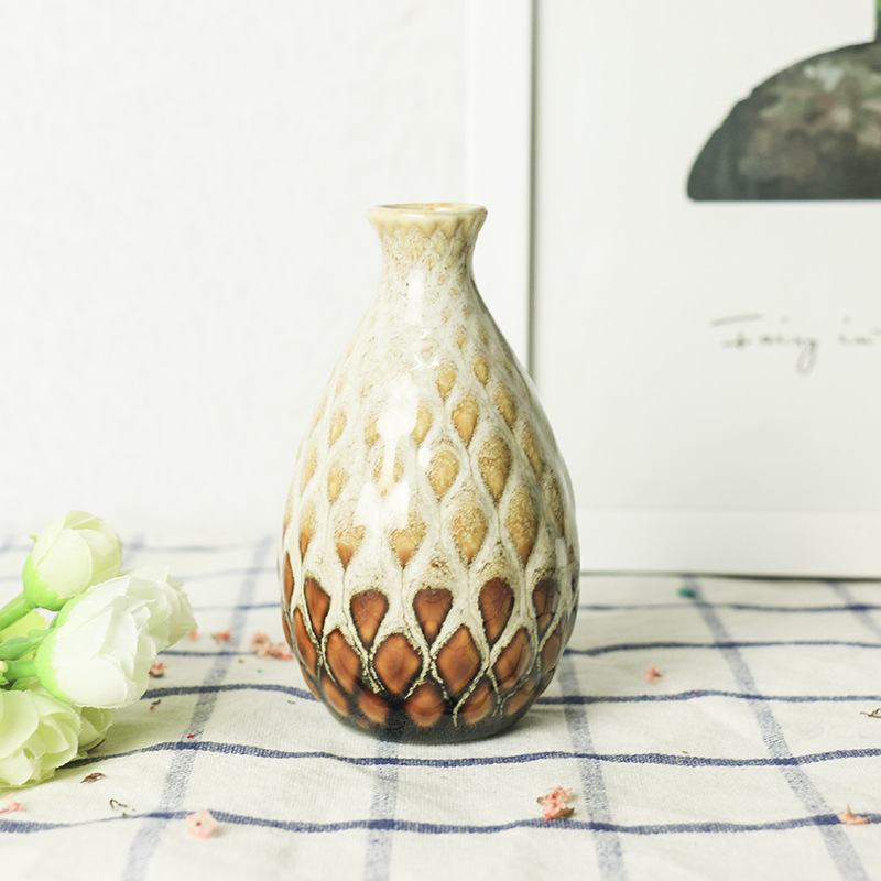 Mini ceramic vase with dried stems anchoring a styled living room shelf
