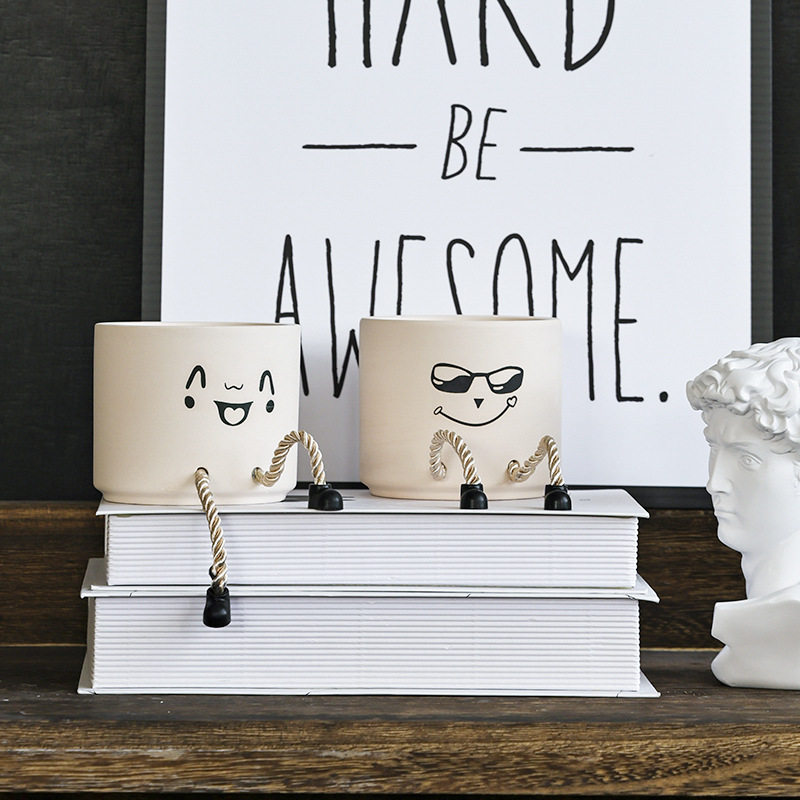 Two cream ceramic face pots, one smiling and one wearing sunglasses