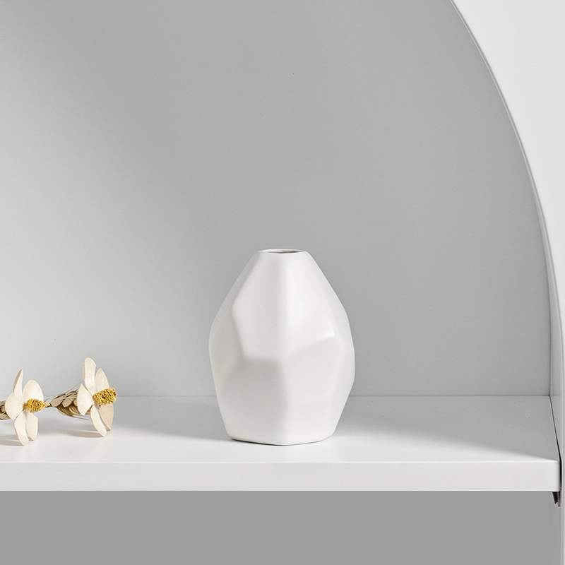 Small faceted ceramic vase holding one slim stem on a home surface