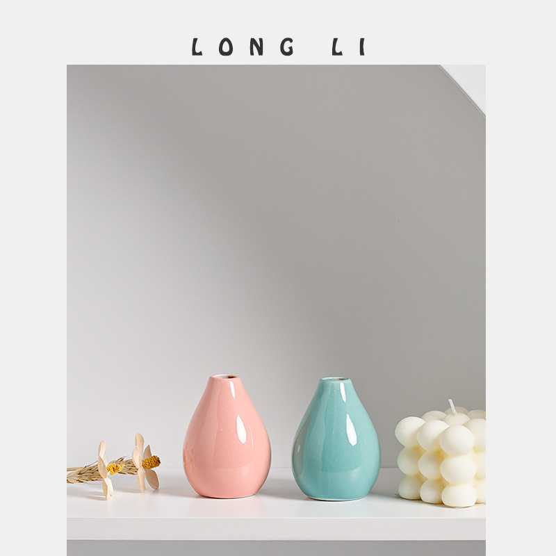 Pink and aqua teal mini ceramic vases styled with a dried flower and candle