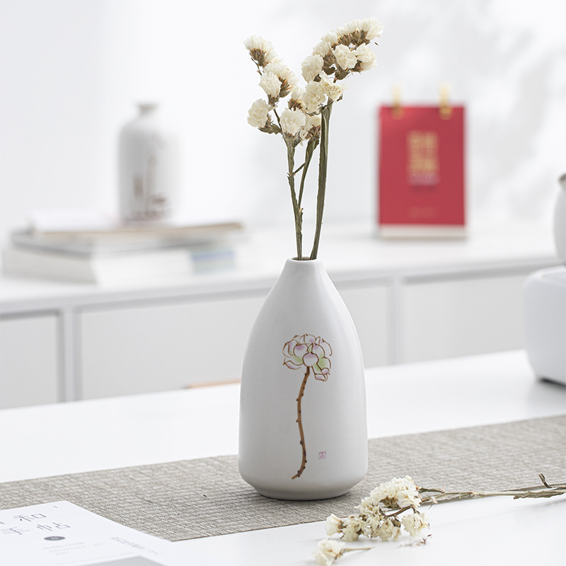 Pear-shaped white ceramic vase with pink lotus holding dried white statice