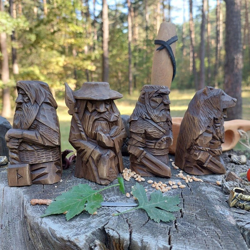 Close view of four carved Norse figures with scattered grain