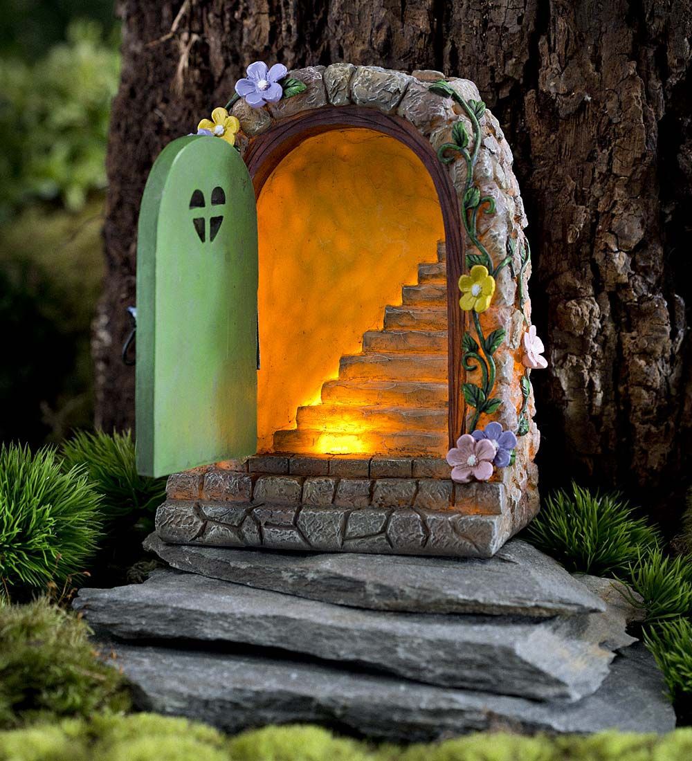Fairy door with green door open revealing a lit stone staircase inside