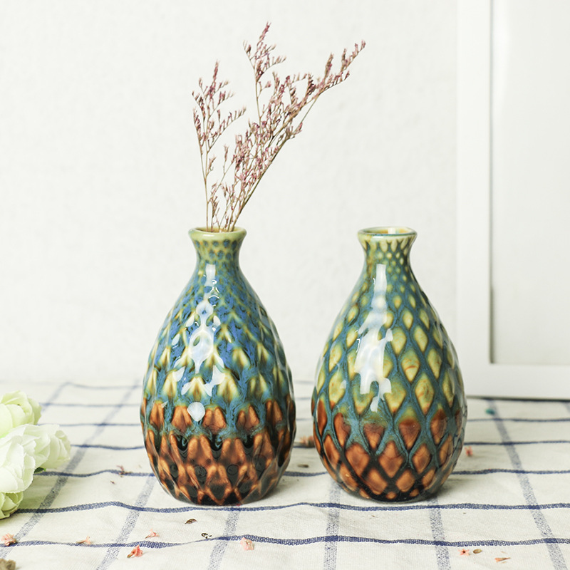Ceramic vase holding dried flower stems on a checked cloth