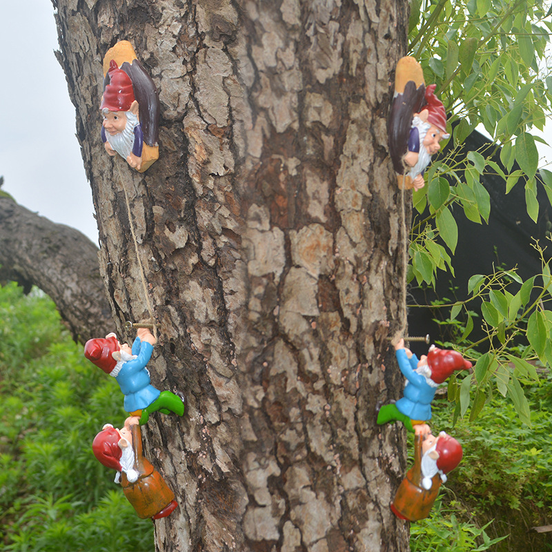 Gnome climbers placed along a large tree trunk surrounded by green plants