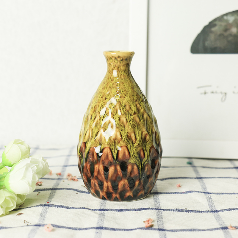 Olive-yellow ceramic vase with drip glaze beside white flowers