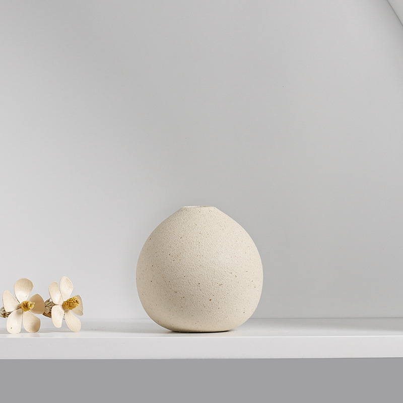 Small cream ceramic vases arranged on a shelf