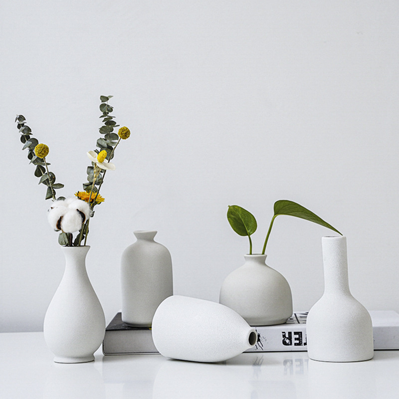 Five matte white ceramic bud vases holding dried cotton, billy buttons and eucalyptus