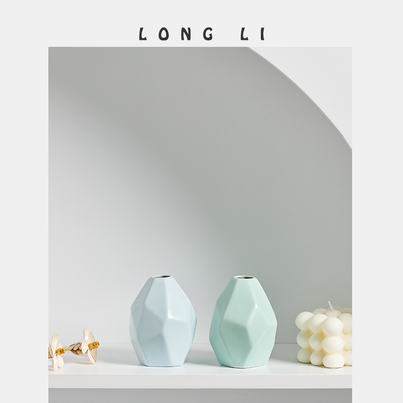 Blue and mint faceted vases styled beside dried flowers and a white candle