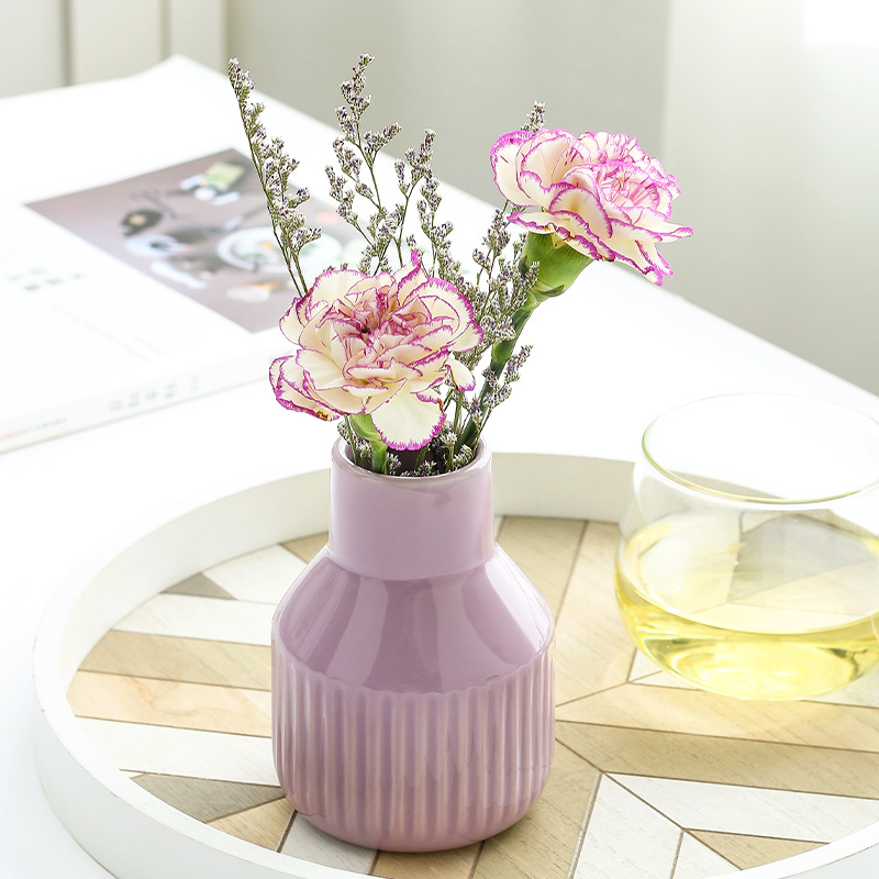 Lilac ribbed vase with pink carnations and dried statice on a round tray