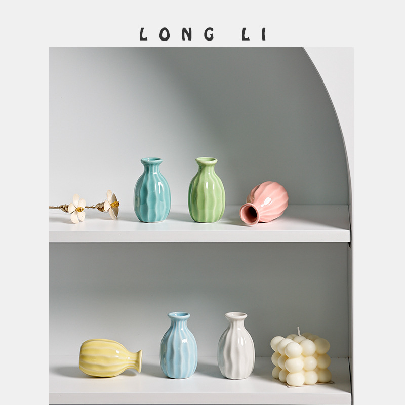 Mini ceramic vases styled on a shelf beside dried white flowers and a candle