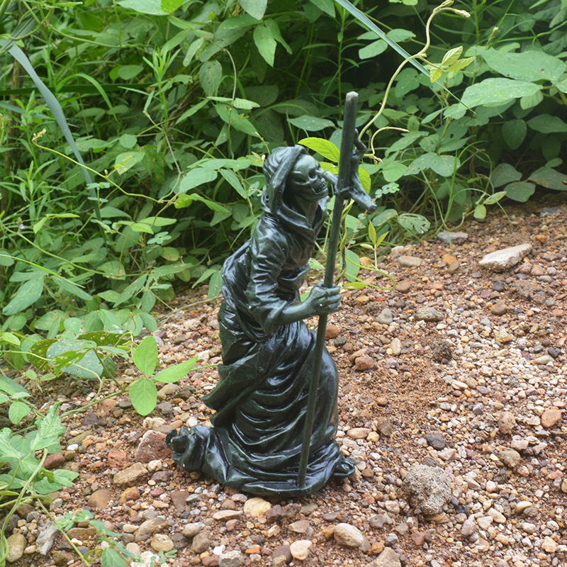 Side profile of the black resin reaper with hooded robe and staff in hand