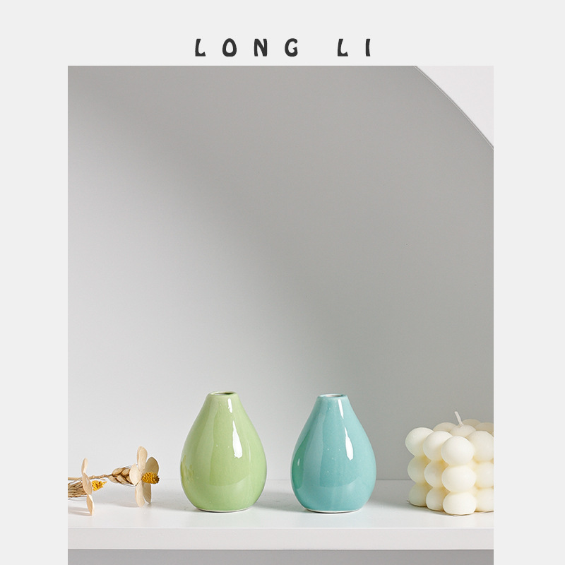 Sage green and aqua teal mini ceramic vases close-up on a white shelf