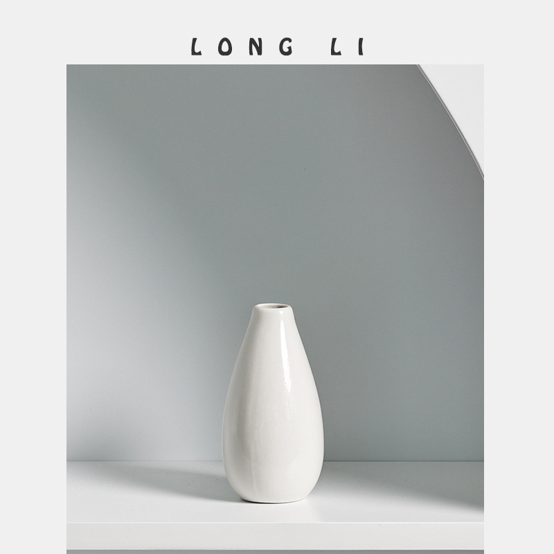 Ivory ceramic vase with glossy glaze on a white shelf