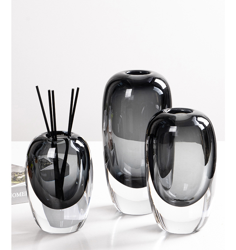 Grey glass vases beside a black reed diffuser with sticks