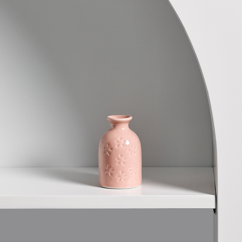 Single pink mini ceramic vase on a white shelf in an arched alcove