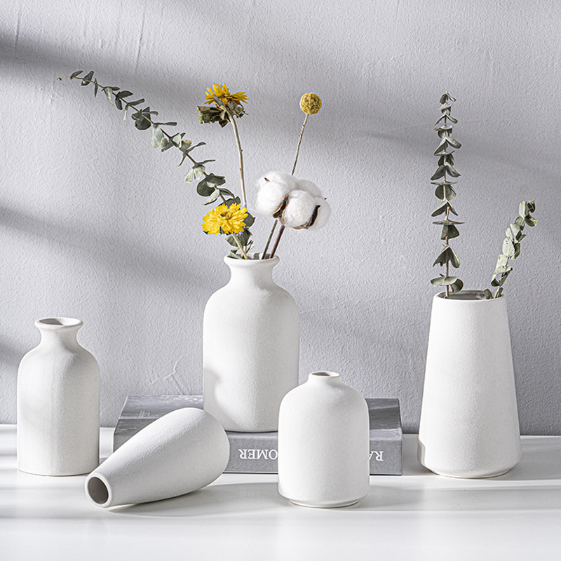 Five matte white vases showing the sandy texture of the glaze across the set