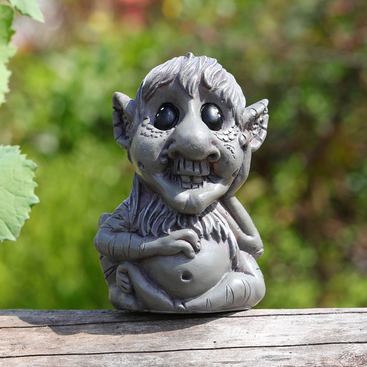 Side-angle view of grey resin troll with raised hand and pointed ear