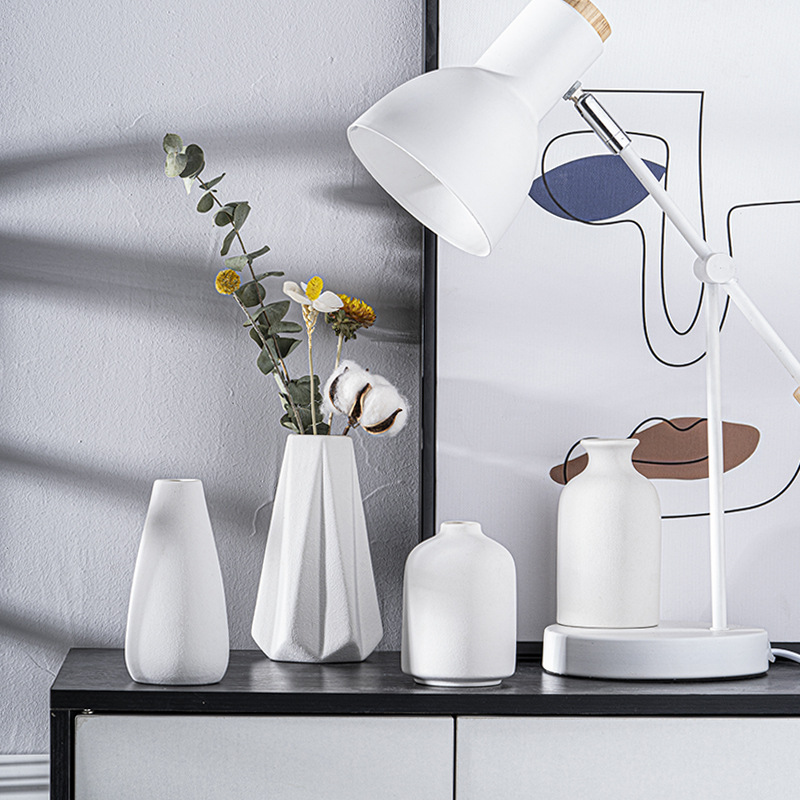 Round and tapered white ceramic vases of different heights on a modern sideboard