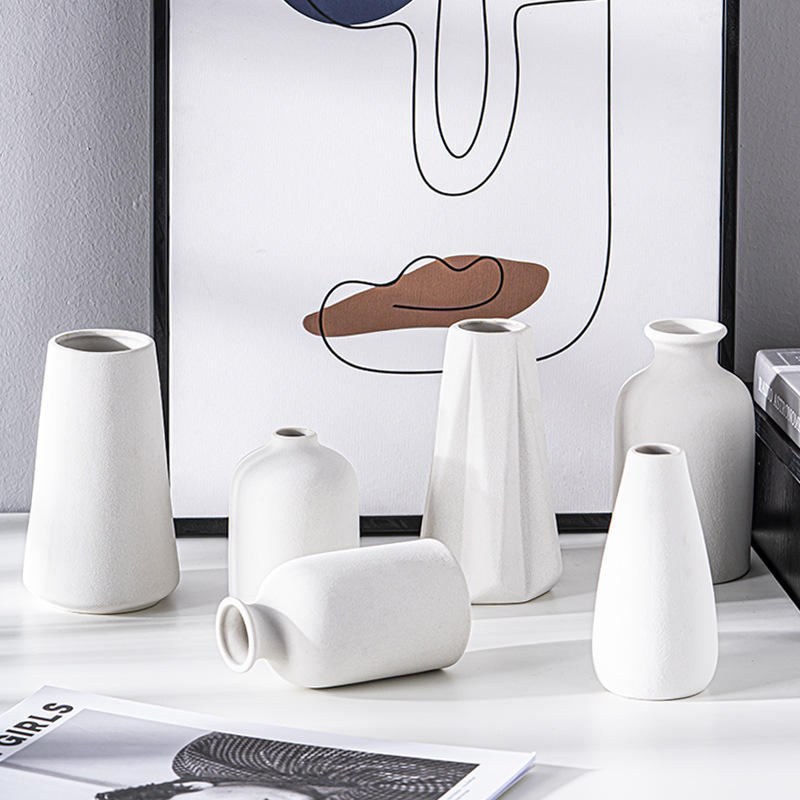 Faceted and bottle shaped white vases with dried stems in matching glaze