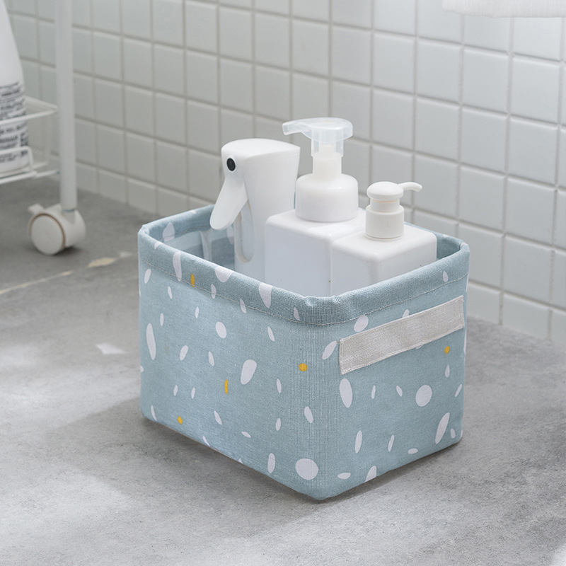Blue-grey basket on a bathroom counter holding bottles against white tiles