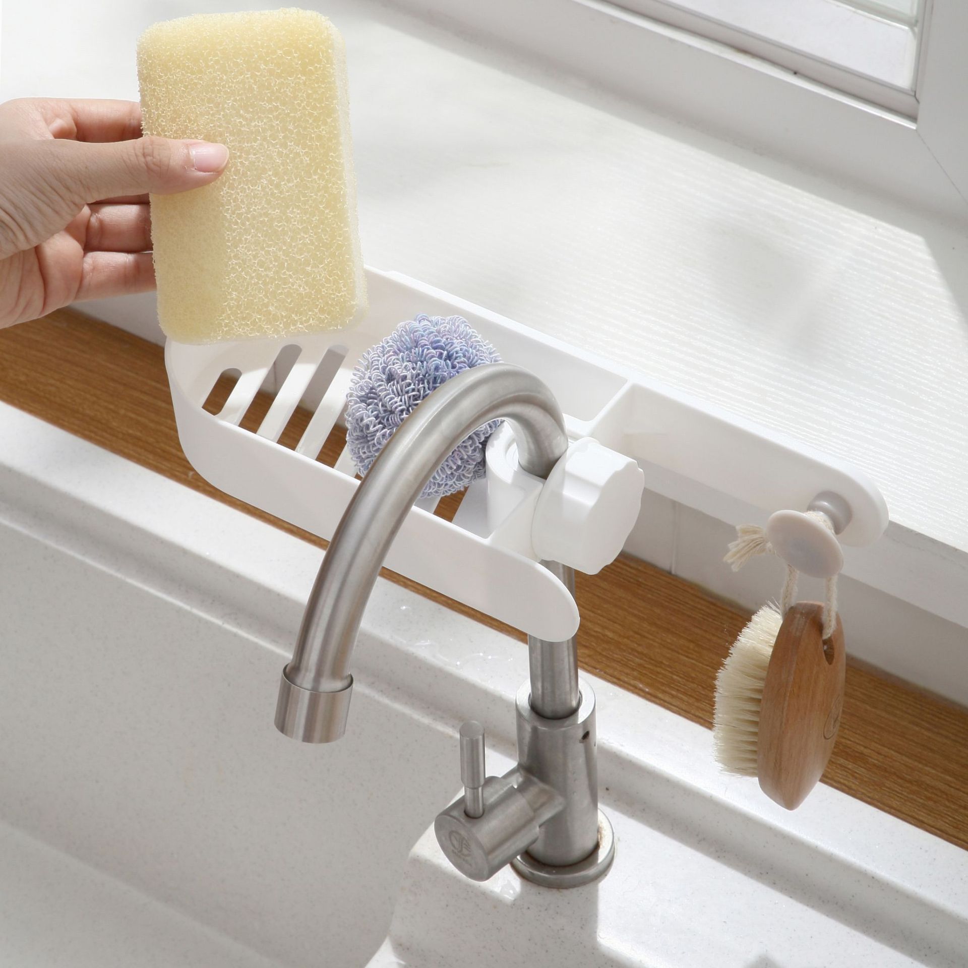 White faucet rack with slotted tray holding a sponge and a scrubber