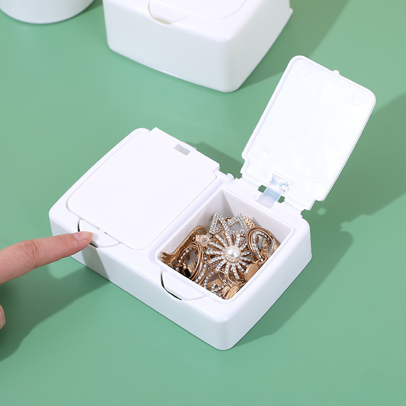 Finger pressing the latch of the organizer with the lid open to show jewelry