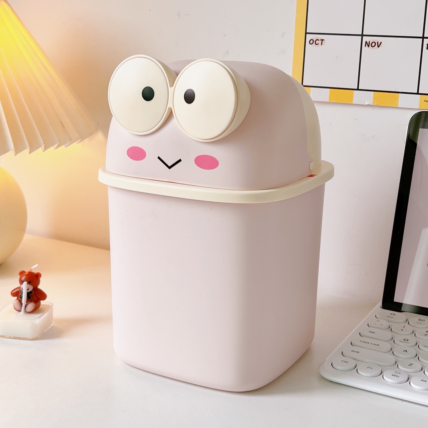 Compact frog desk trash can angled beside a keyboard for scale
