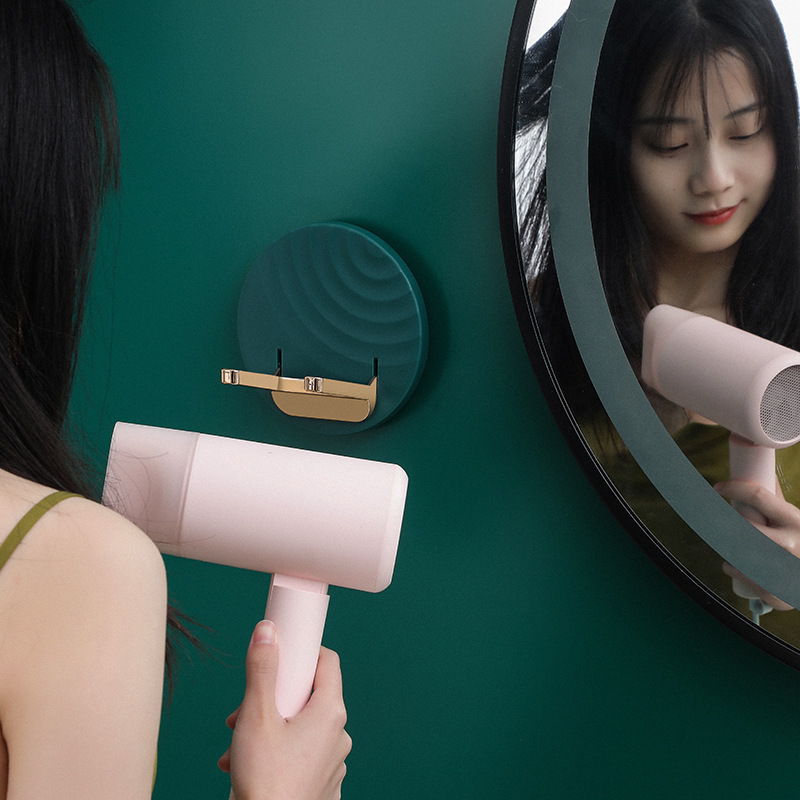 Woman reaching for a pink dryer on a wall holder beside the mirror