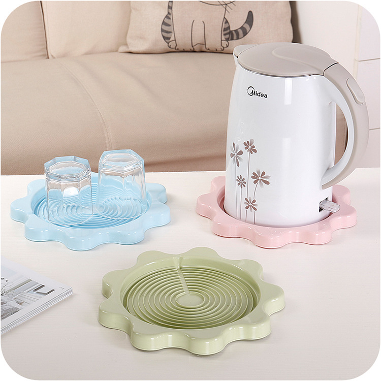 Two glasses on a blue flower pad with a kettle on the pink pad