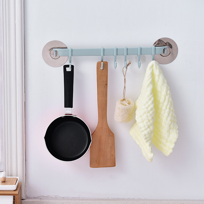 Pastel rail on a kitchen tile wall holding a pan, spatula and towel