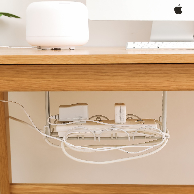Cords and a power strip sitting out of sight under a wooden desk
